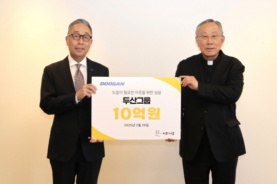 박지원 두산그룹 부회장(사진 왼쪽)과 구요비 재단법인 바보의 나눔 이사장이 26일 서울 명동성당에서 열린 성금 전달식에서 기념촬영을 하고 있다. 두산그룹 제공